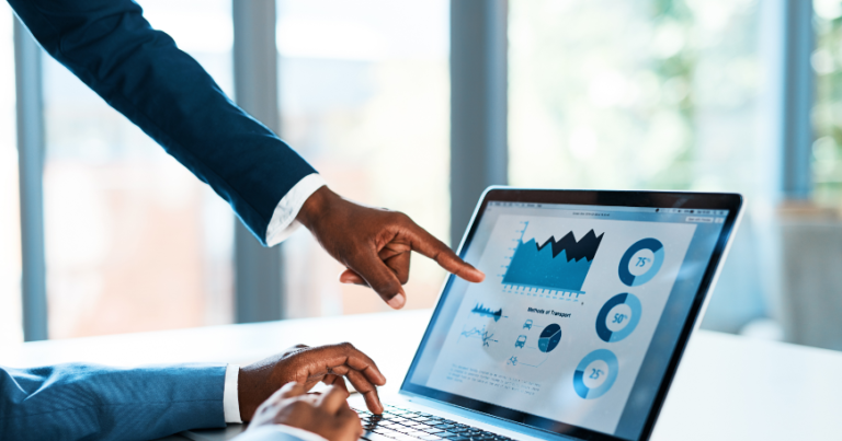 Two people review graphs and charts on a laptop screen; one person types while the other points at data visualisations.